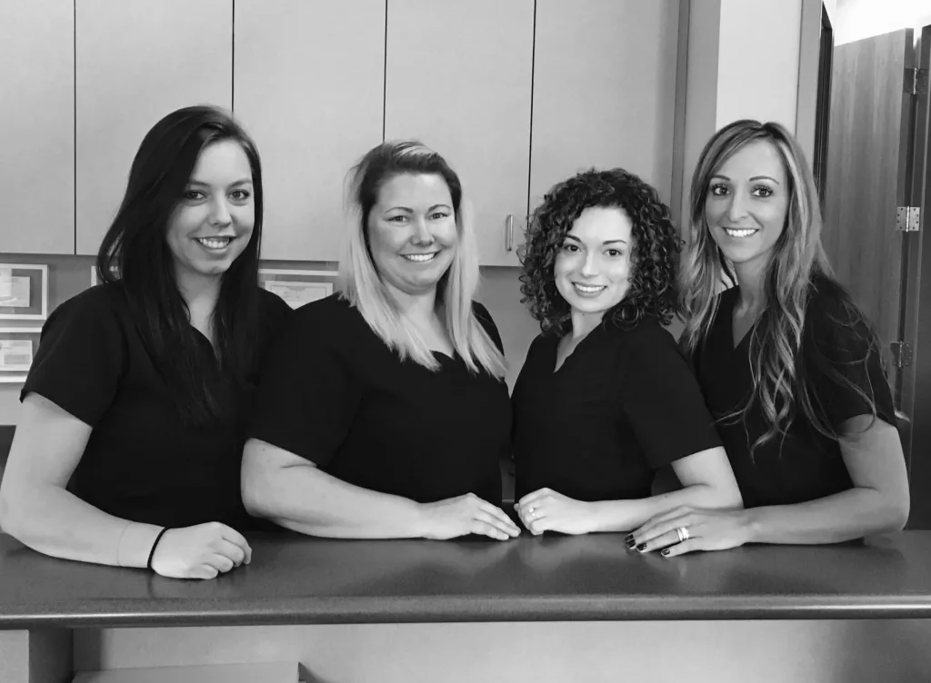 Black and white picture of the staff standing behind the front desk